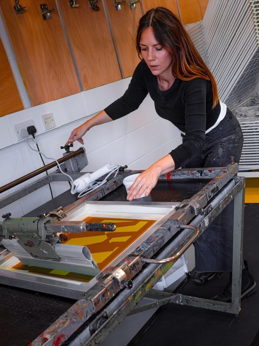 Charlotte Whiston pulling a print on the screen press at flood and pull.