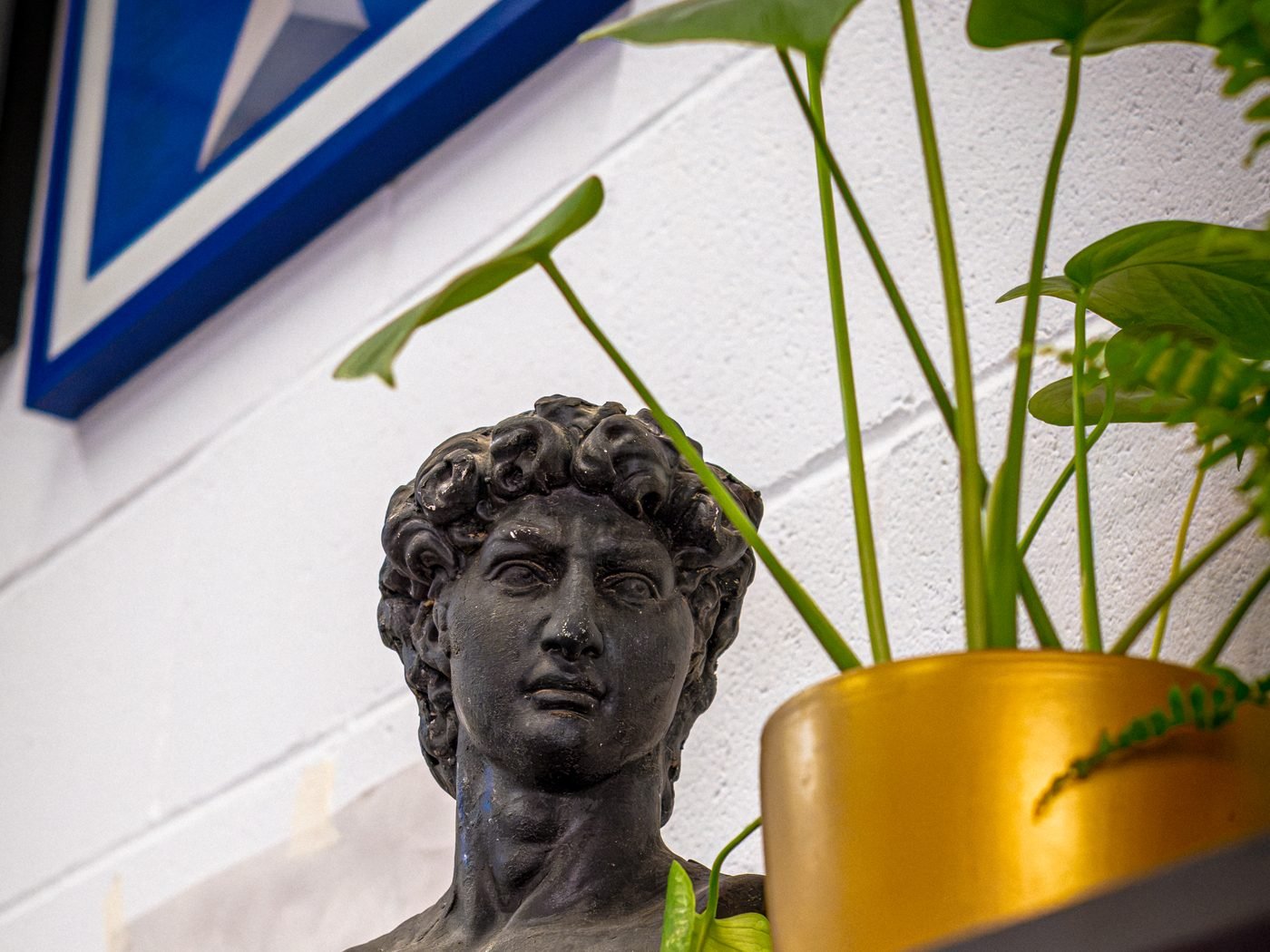 Studio shelf detail at flood and pull., with a plaster bust and framed print.