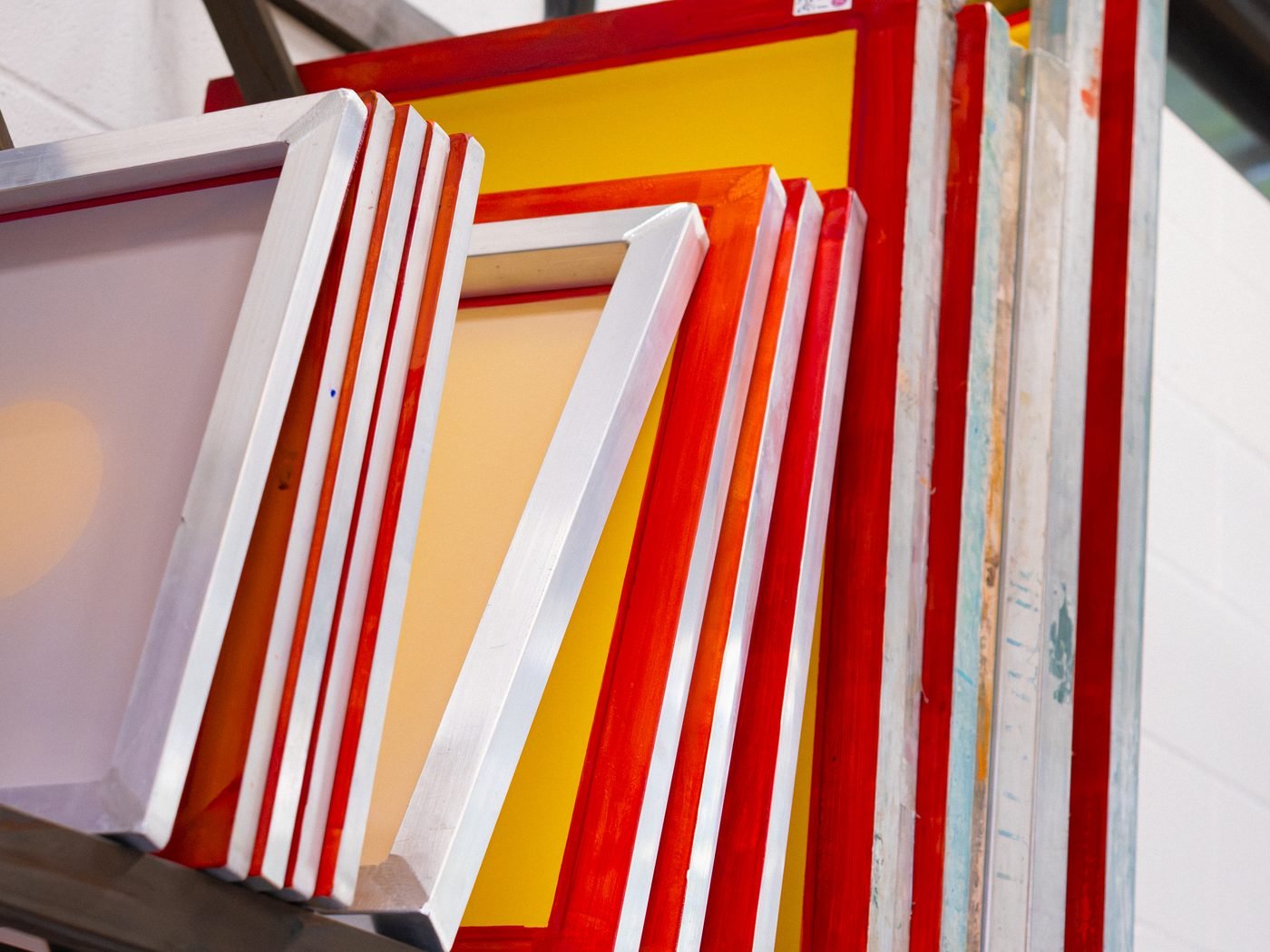 A rack of screen printing frames ready for use at flood and pull. studio.